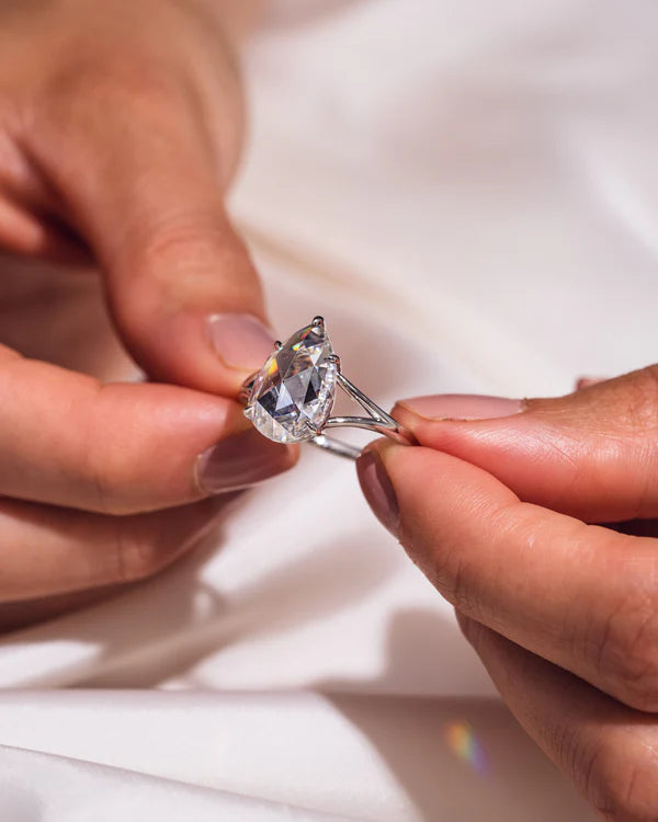 Detalle de anillo pear 1.50 ct con banda dividida y engaste de garras en oro.