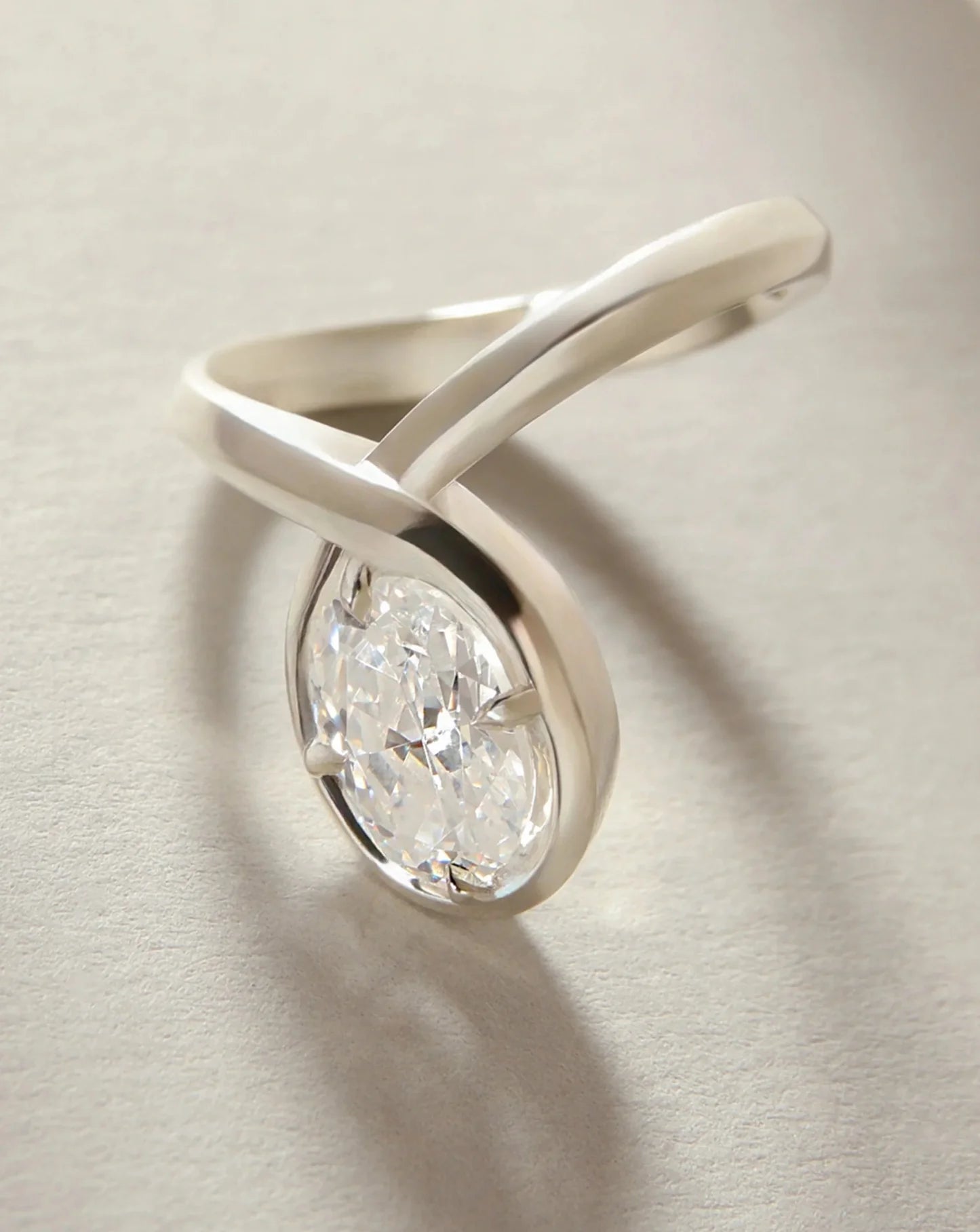 Detalle de anillo oval con diamante lab-grown en engaste bezel y brazo cruzado moderno.