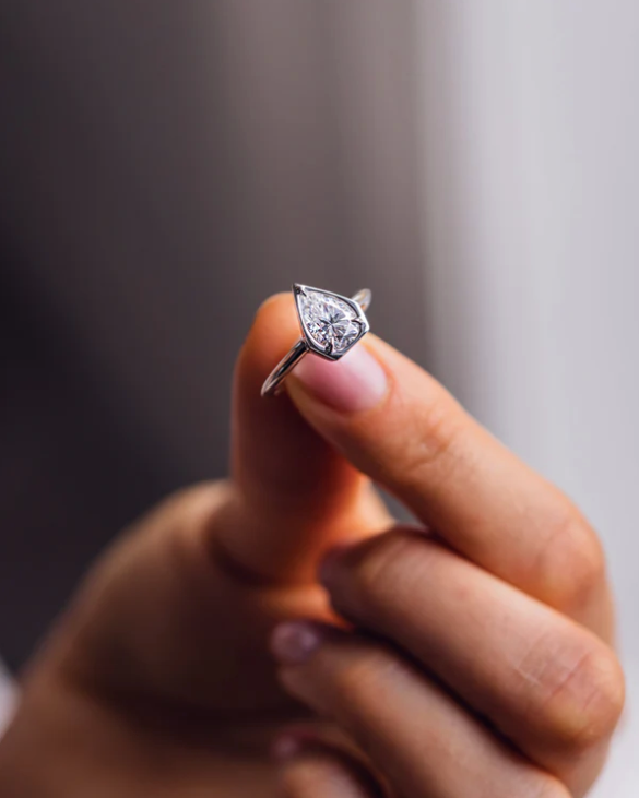Detalle de anillo pear 2.5 ct con bisel abierto, diseño contemporáneo y elegante.