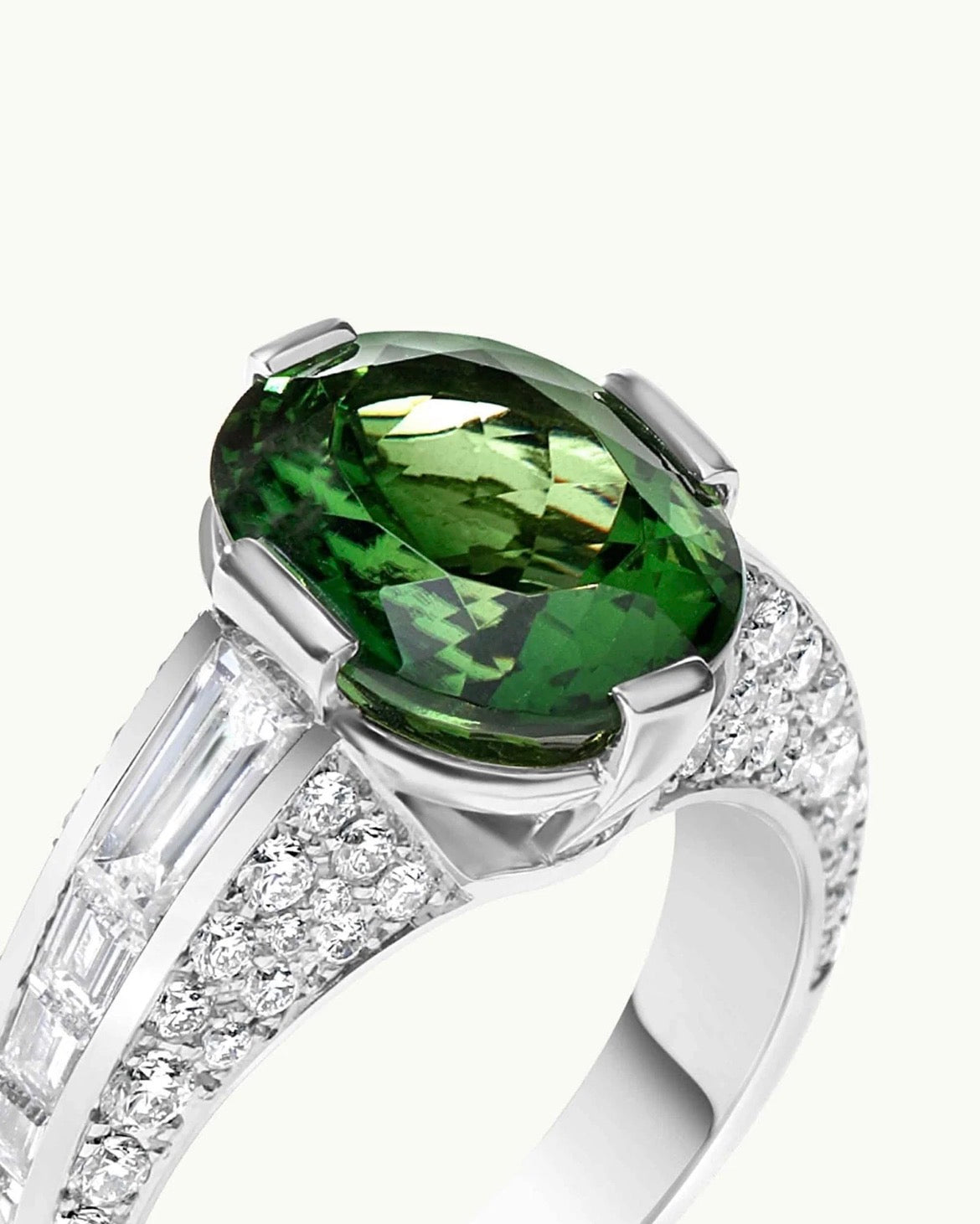 Detalle de anillo oval verde fancy con diamantes laterales incoloros y diseño de alta joyería.